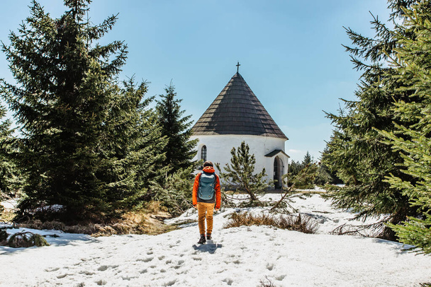 Backpacker at Baroque Chapel of the Visitation of the Virgin Mary, Kunstat Chapel, located in Eagle Mountains at height of 1035 m, Czech Republic.Circular floor plan and roof covered with shingles. - Фото, зображення