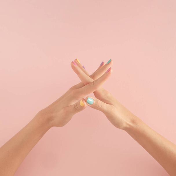 ženy ruce s barevnými nehty na pastelově růžovém pozadí. kopírovat prostor. léto moderní tropické abstraktní umění s ženskou rukou. minimální nápad pozadí. - Fotografie, Obrázek