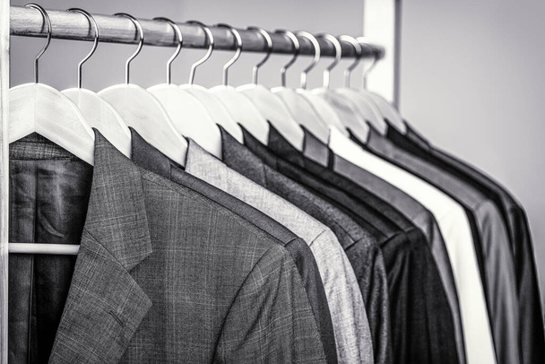 Pánské košile, skafandr pověšený na stojanu. Věšáky s bundami v butiku. Obleky pro muže zavěšené na stojanu. Černá a bílá - Fotografie, Obrázek