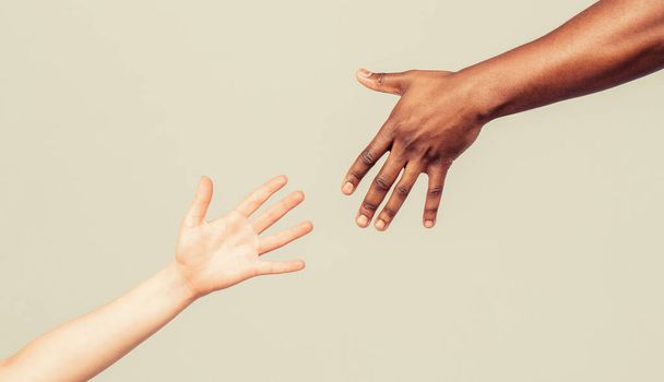 Um gesto de resgate. Mãos humanas pretas e brancas. Mãos africanas e caucasianas. Dar uma mão amiga a outro. Mulher e mulher africana mão - Foto, Imagem