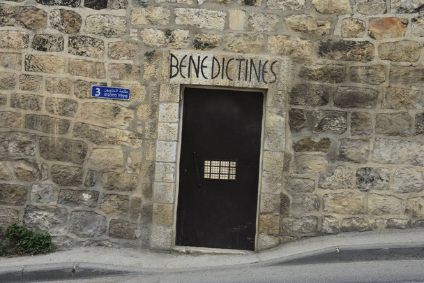 Jerusalén Israel 27 de marzo de 2021: puerta metálica con la inscripción Benedictina, antigua muralla de ladrillos blancos. Foto de alta calidad - Foto, imagen