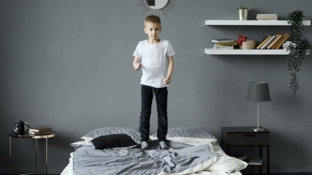 šťastný chlapeček v pyžamu skočí ráno na postel svých rodičů. Šťastné dětství pro děti s milující rodinou. Aktivní dítě. - Záběry, video