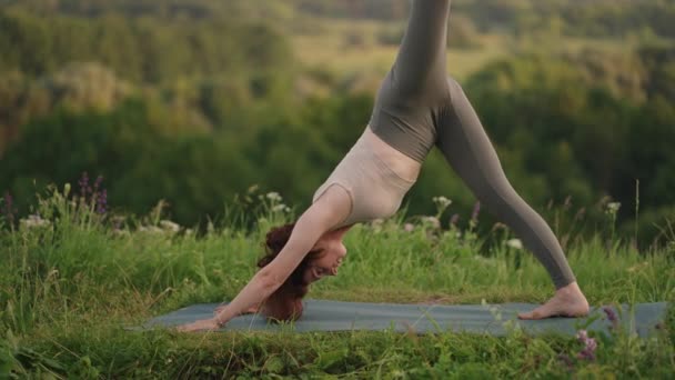 Un maestro di yoga fa esercizi per l'equilibrio e lo stretching. La pace e la scorrevolezza dei movimenti di una ragazza che fa yoga in montagna nella foresta - Filmati, video