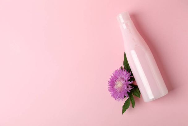 Blank bottle of shampoo and flower on pink background - Foto, afbeelding