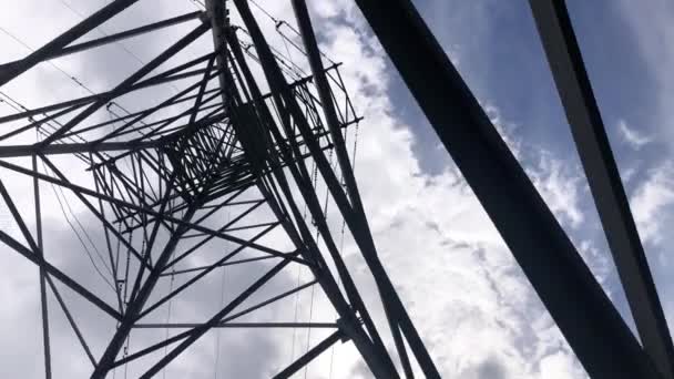 Проверка металлического столба высокого напряжения снизу вверх на фоне голубого неба. Электрические сети для передачи и транспортировки электроэнергии - Кадры, видео