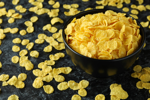 Schüssel Cornflakes und bestreute Cornflakes auf schwarzem Rauchhintergrund - Foto, Bild