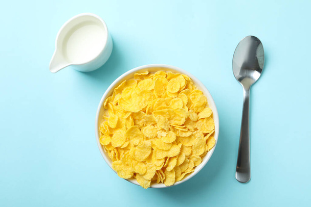 Concepto de sabroso desayuno con copos de maíz sobre fondo azul - Foto, imagen