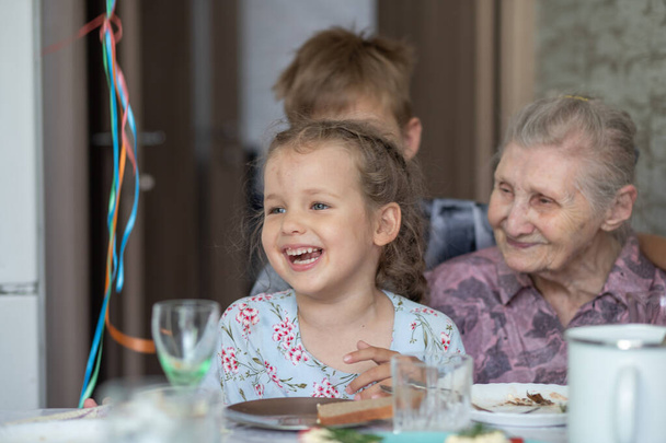 La abuela y sus nietos en la fiesta de cumpleaños, la abuela tiene 90 años, los niños felicitan a la anciana. - Foto, Imagen
