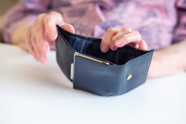 Yaşlı bir kadının elleri boş bir siyah cüzdan tutuyor, büyükannesi cüzdana küçük paralar koyuyor, yoksulluk konsepti, parasızlık.... - Fotoğraf, Görsel