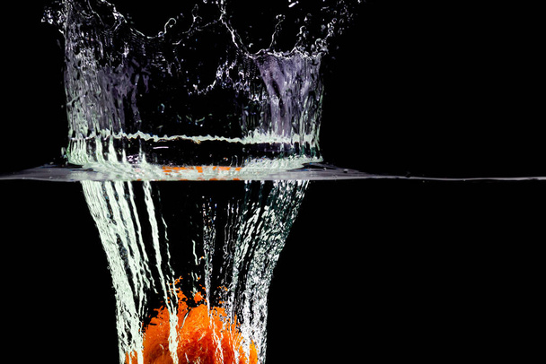 one orange fell into the water with splashes and bubbles - Foto, afbeelding
