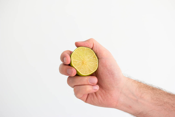 Limão fresco verde metade realizada na mão por mão masculina caucasiana close-up tiro isolado no branco. - Foto, Imagem