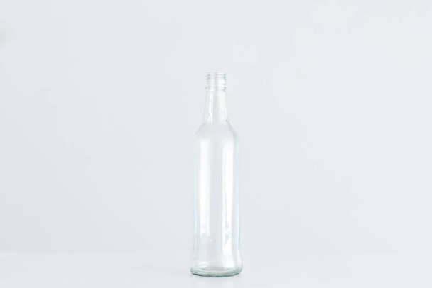 Empty clear glass bottle isolated on light gray background. - Фото, изображение