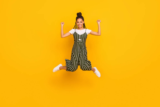 Full size profile side photo of young afro girl happy positive smile jump rejoice win victory isolated over yellow color background - Valokuva, kuva