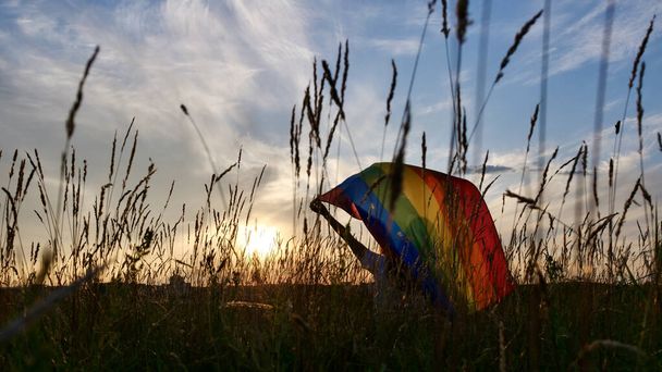 Γυναίκα με σημαία ΛΟΑΤ στο φόντο ουρανό ηλιοβασίλεμα - Φωτογραφία, εικόνα