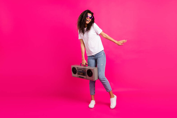 Full size photo of cute lady hold boom box look empty space wear spectacles t-shirt jeans sneakers isolated on pink background - Φωτογραφία, εικόνα