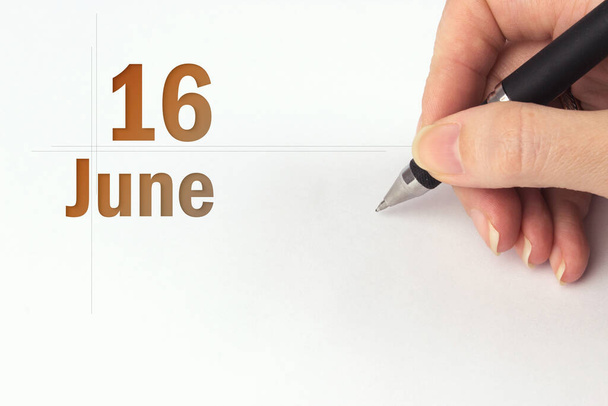 Le 16 juin. Jour 16 du mois, date du calendrier. La main tient un stylo noir et écrit la date du calendrier. Mois d'été, concept de jour de l'année - Photo, image