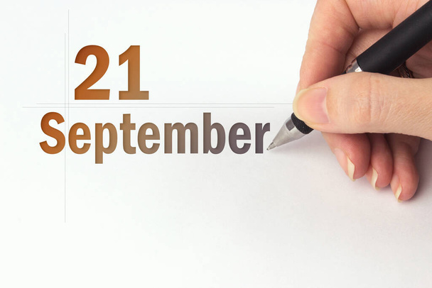 21 Σεπτεμβρίου. Ημέρα 21 του μήνα, ημερομηνία ημερολογίου. Το χέρι κρατά ένα μαύρο στυλό και γράφει την ημερομηνία ημερολογίου. Φθινόπωρο μήνας, ημέρα του έτους έννοια - Φωτογραφία, εικόνα