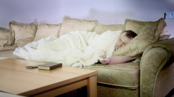 Mies makaa sohvalla yöllä katsomassa televisiota, katsomassa elokuvaa, iltavalaistus - Materiaali, video