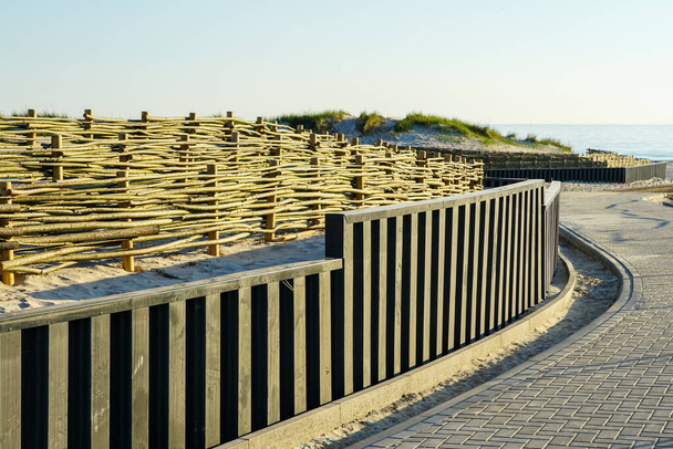 protección de la infraestructura de playa contra el movimiento de dunas de arena con nueva barrera de madera de ramas de sauce de mimbre - Foto, imagen