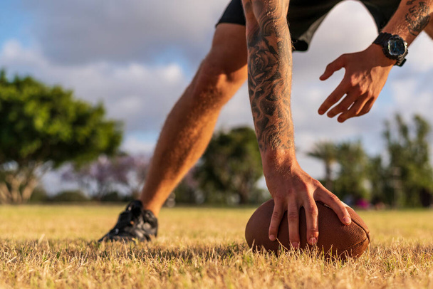 23.05.2020. American football ball in players hand on green lawn - Foto, immagini