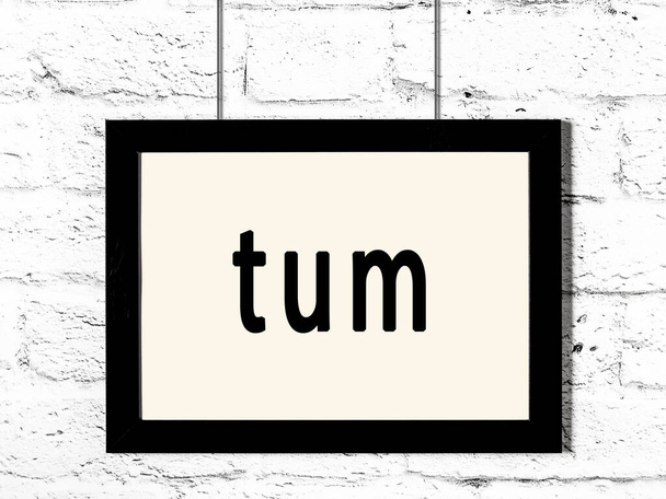 Černý dřevěný rám s nápisem Tum visí na bílé cihlové zdi  - Fotografie, Obrázek