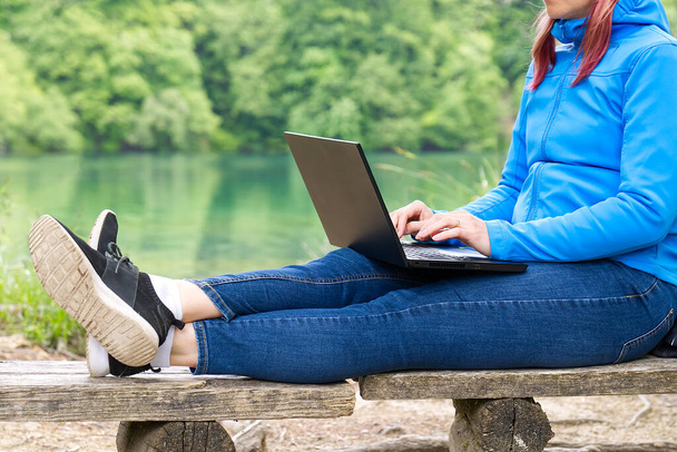 Fiatal nő, női szabadúszó dolgozik laptop Gyönyörű kilátás nyílik az erdőre és a tóra. - Fotó, kép