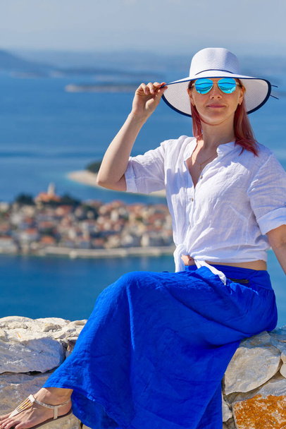 Tourist woman in a white straw hat on beautiful blue Adriatic Sea and cozy island background Croatia - Photo, Image