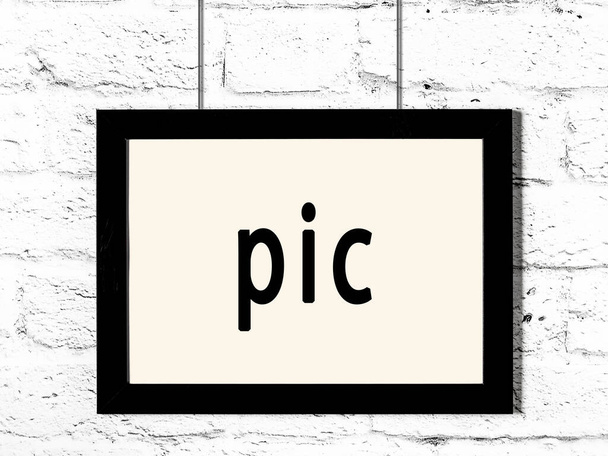 Černý dřevěný rám s obrázkem nápisu zavěšeným na zdi z bílých cihel  - Fotografie, Obrázek