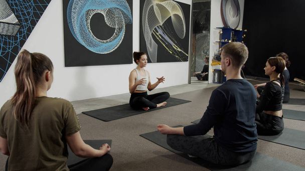 Спортивная молодая женщина медитирует, сохраняя социальную дистанцию с друзьями - Фото, изображение