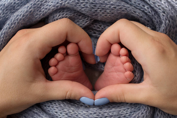 Füße eines Neugeborenen in Großaufnahme in einer Wolldecke. Schwangerschaft, Mutterschaft, Vorbereitung und Erwartung der Mutterschaft, das Konzept der Geburt eines Kindes.  - Foto, Bild