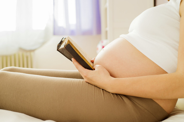 Pregnant woman reading book - Foto, afbeelding