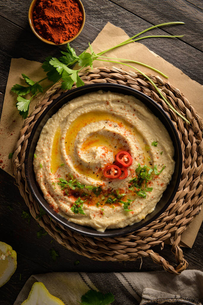 Delicious hummus in ceramic bowl. Colorful snack composition on a black wooden background. - Fotografie, Obrázek