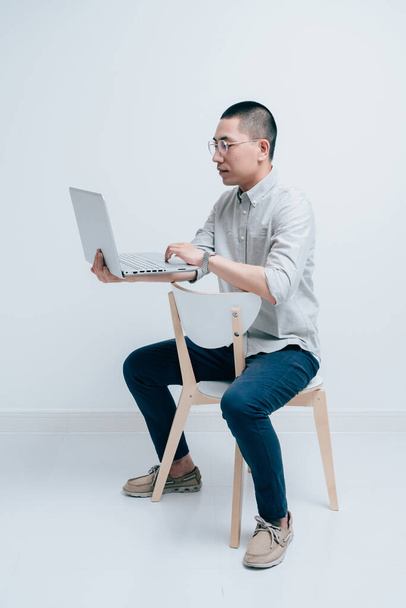 Los hombres jóvenes con camisas grises trabajan con computadoras portátiles - Foto, imagen
