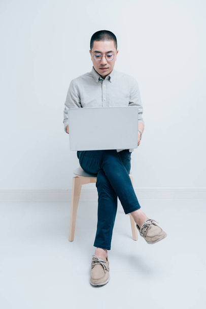 Молодые люди в серых рубашках работают с ноутбуками - Фото, изображение