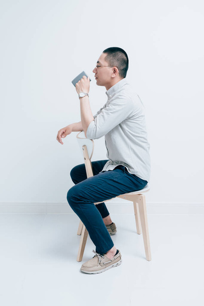Jovem macho segurando um copo de água sentado em uma cadeira - Foto, Imagem