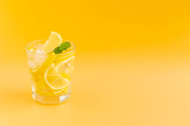 Детокс Води з лимоном у склянці на оранжевому фоні.. - Фото, зображення
