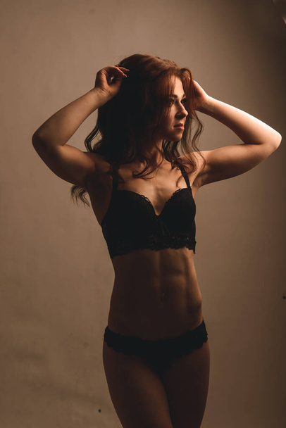 Schöne athletische Frau schüttelt ihre Bauchmuskeln auf einem Studiohintergrund - Foto, Bild