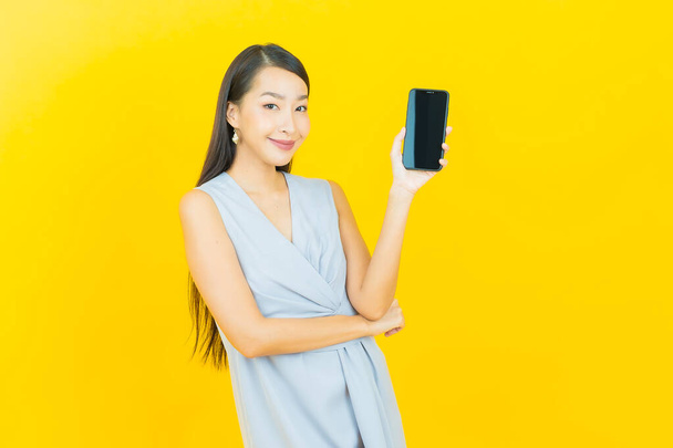 Portrait beautiful young asian woman smile with smart mobile phone on color background - Valokuva, kuva