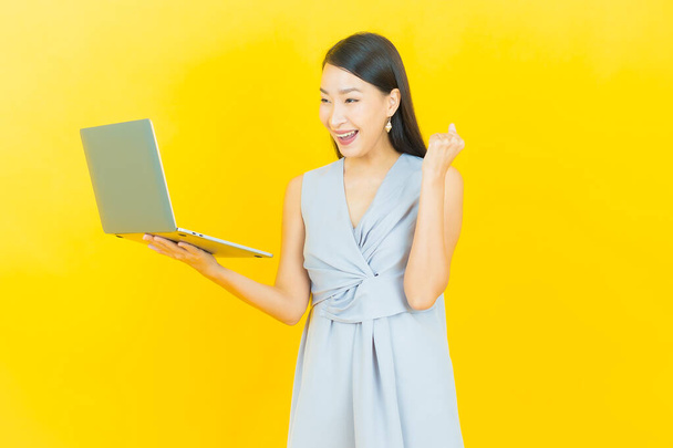 Портрет красива молода азіатка посміхається з комп'ютерним ноутбуком на ізольованому фоні
 - Фото, зображення