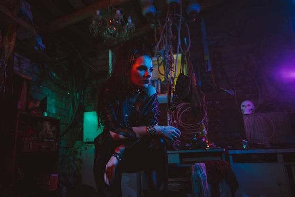 Cyberpunk κορίτσι σε ένα μετα-αποκαλυπτικό φουτουριστικό στυλ σε ένα γκαράζ - Φωτογραφία, εικόνα