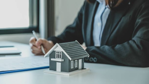 home model. Hand signing on contract after the real estate agent explains the business contract, rent, purchase, mortgage, loan, or home insurance to the buyer. - 写真・画像
