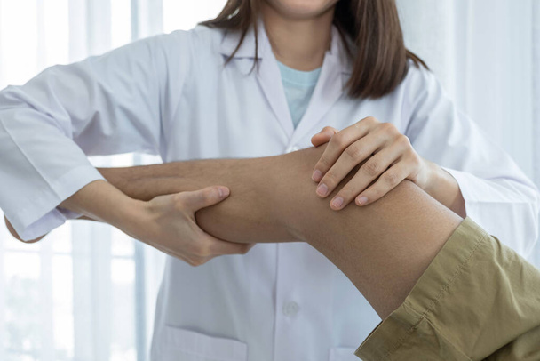 Жіночі руки лікаря роблять фізичну терапію Розширюючи ногу і коліно пацієнта чоловічої статі
. - Фото, зображення