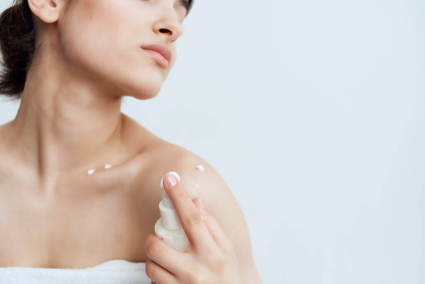 vrouwen met blote schouders lotion toe te passen op de gezondheid van de huid levensstijl - Foto, afbeelding