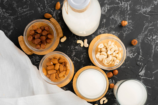 diverse noten zoals amandel, cashew, hazelnoot en melk in een glazen fles, gezond voedsel - Foto, afbeelding