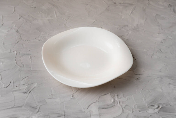 placa cerâmica limpa vazia ou prato em uma superfície de concreto, conceito de artigo de mesa, simular - Foto, Imagem