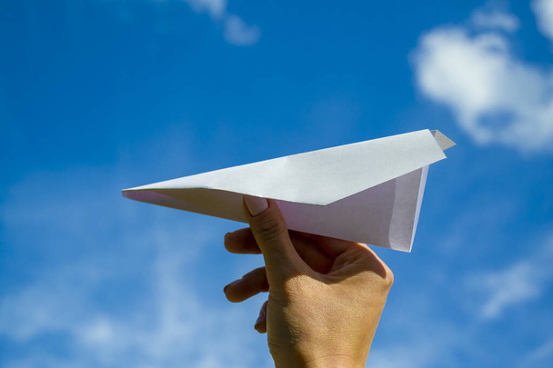 papírové letadlo v ruce ženy proti modré obloze - Fotografie, Obrázek