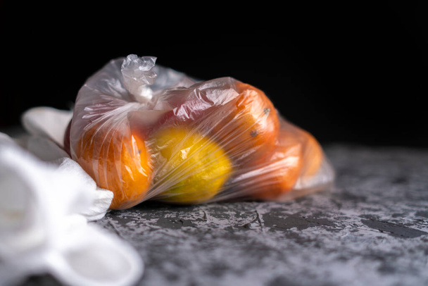 frutas estropeadas dañadas en una bolsa en una habitación oscura, concepto de daño de contenedor de plástico b - Foto, Imagen