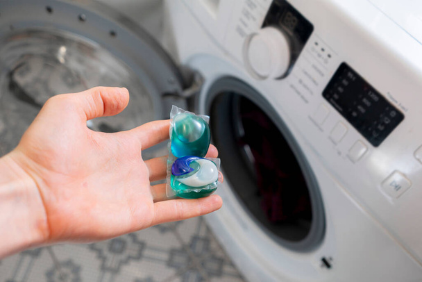 Personen legen spezielle Putzkapseln oder -kapseln mit schmutzigem Tuch in die Waschmaschine - Foto, Bild