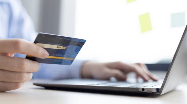 Το δάχτυλο της γυναίκας πατάει ένα πληκτρολόγιο και κατέχει μια πιστωτική κάρτα για να εγγραφείτε για πληρωμές ή online συναλλαγές, χρηματοπιστωτικές συναλλαγές και την ασφάλεια του Διαδικτύου, Αγορές online και τραπεζικές online έννοια. - Φωτογραφία, εικόνα