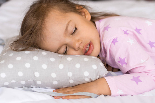 home, comfort, childhood, care, love, sweet dream- little pretty smiling happy authentic toddler sibling kid child girl in pajamas lie rest sleep on bed pillows with closed eyes soft cozy sleepy mood - Photo, image